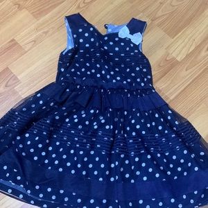 Girls dress blue with white Polka dots.  Has white ribbon on top left.